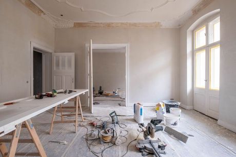 A room under construction with a table and tools on the floor.