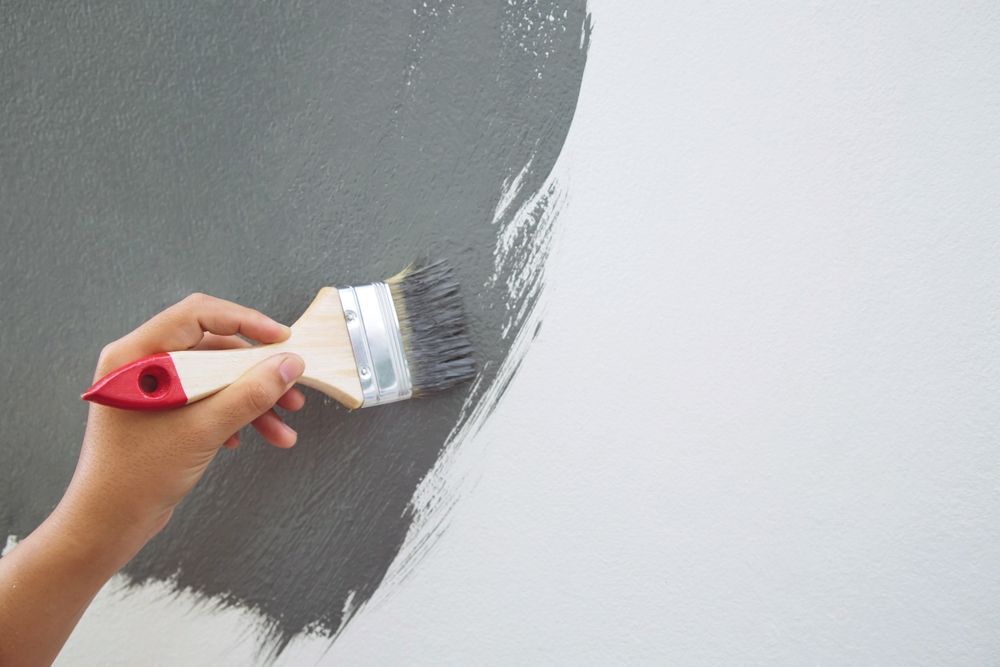 A person is painting a wall with a brush.