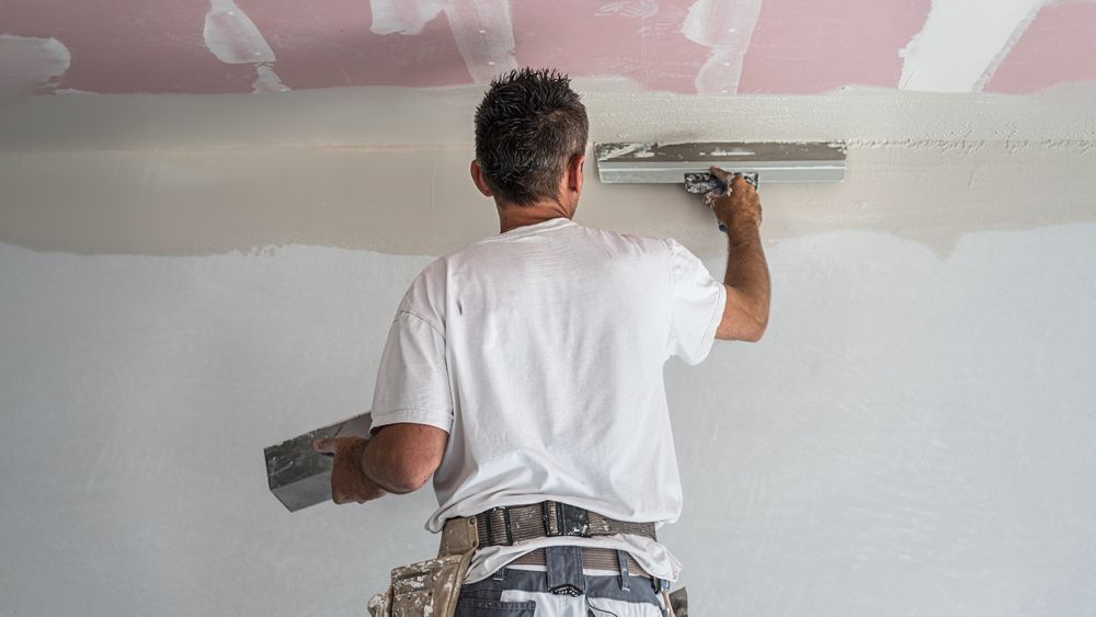 A man is plastering a wall with a trowel.