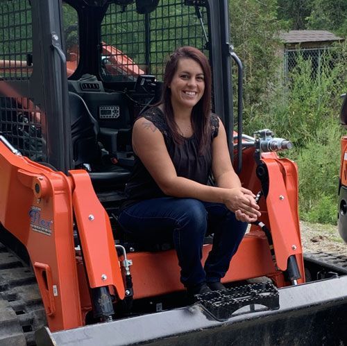 Une femme est assise à l'arrière d'un tracteur orange
