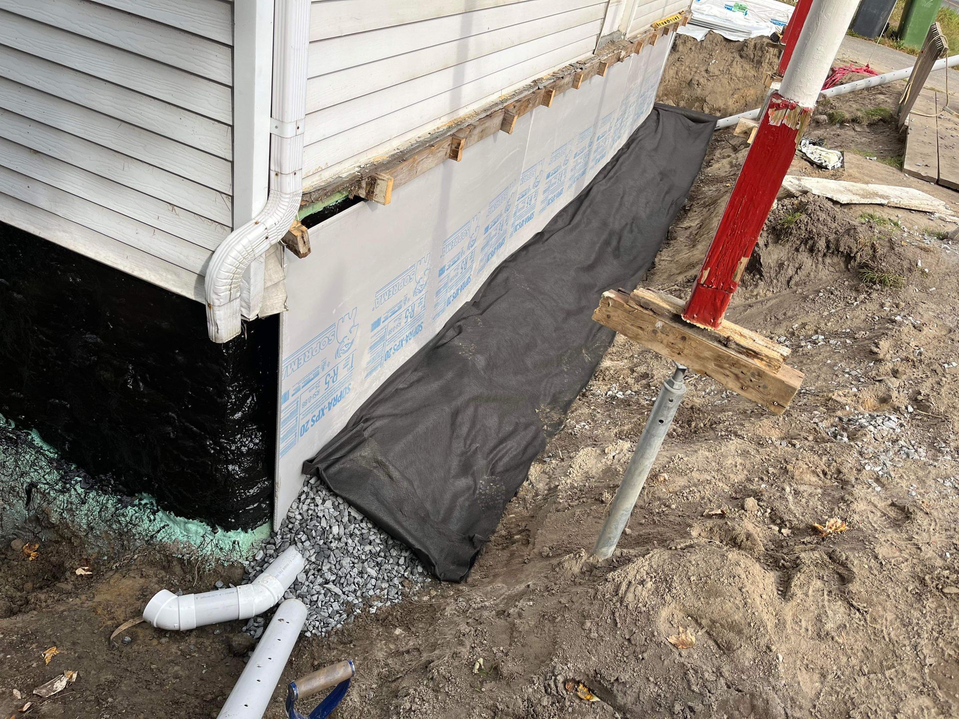 Une maison est en cours de rénovation et les fondations sont en cours d'imperméabilisation.