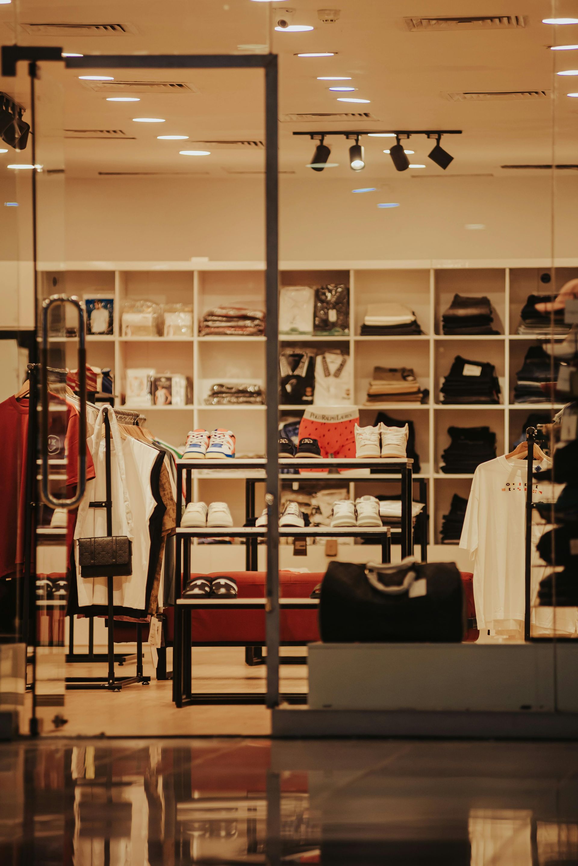 Clothing store interior with shelves of bags and folded apparel under warm lighting