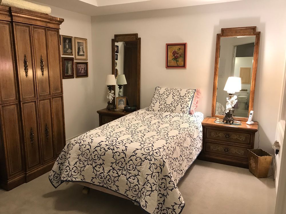 Bedroom with single bed, wooden furniture, and patterned quilt.