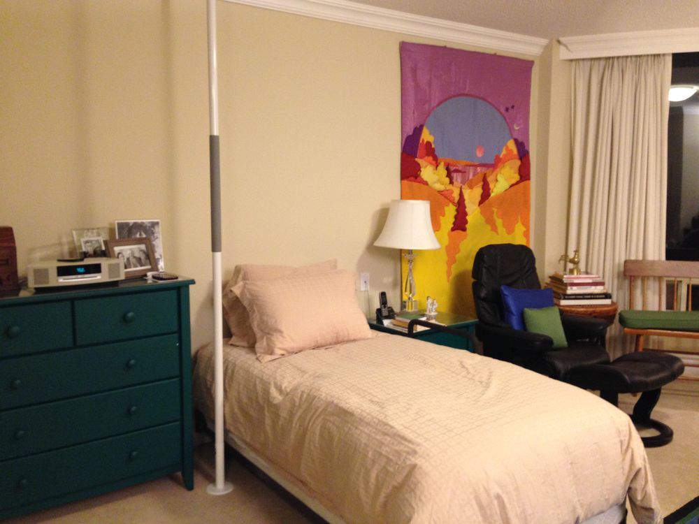 Bedroom with a bed, dresser, chair, wall art, and a pole.