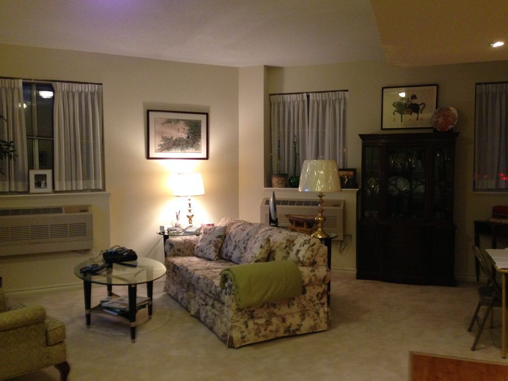Living room with floral sofa, dark cabinet, and windows with curtains.