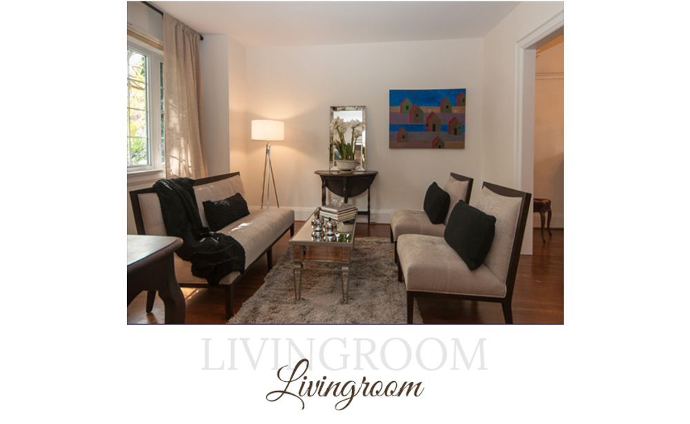 Living room with light-colored walls and furniture. Glass coffee table, rug, and artwork. A standing lamp illuminates the space.