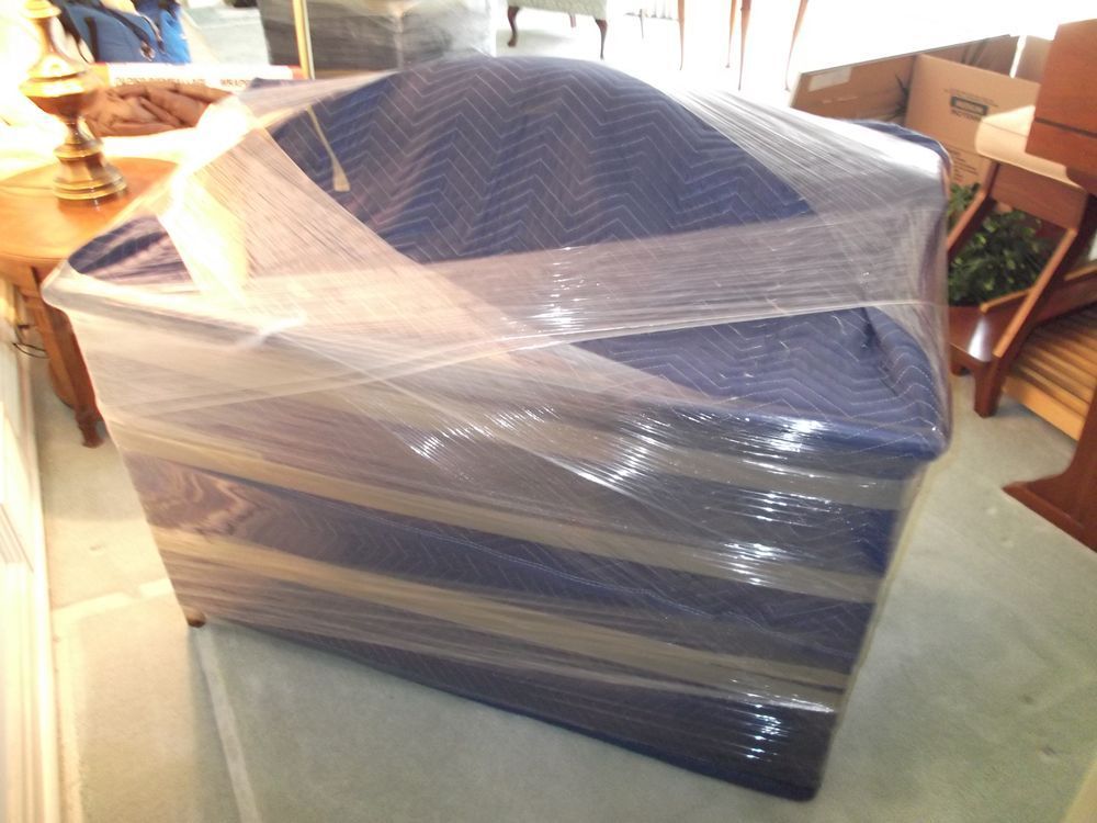 Blue upholstered chair wrapped in plastic and padding, ready for moving.
