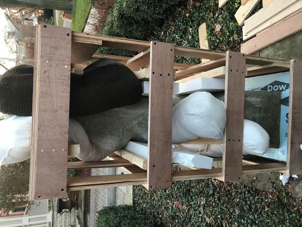 Wooden framed storage unit filled with bags and miscellaneous items outdoors.