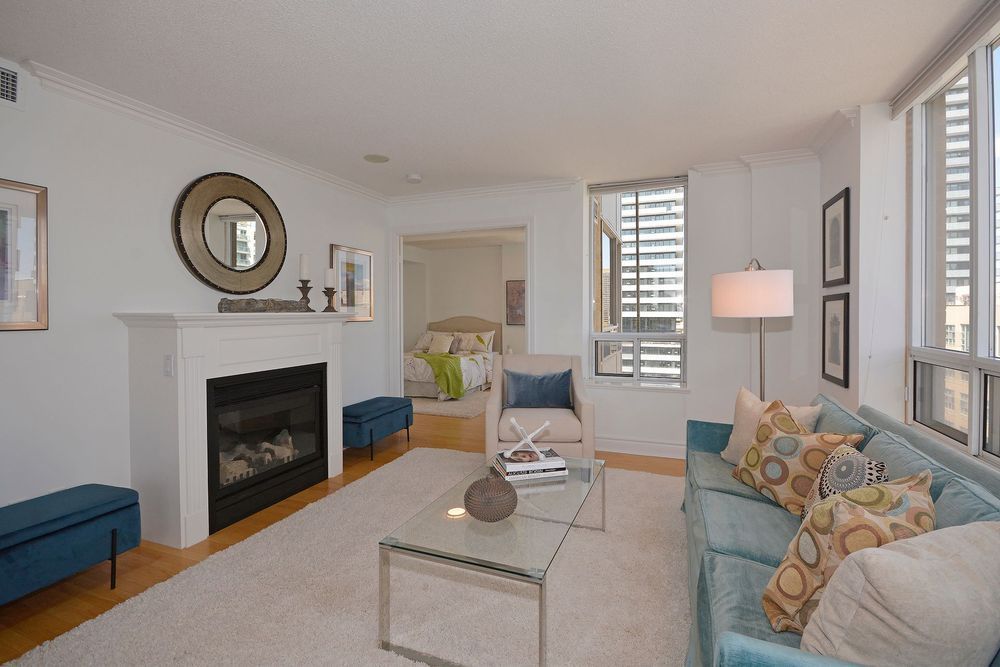 Bright living room with a fireplace, teal sofa, and city view through the window.