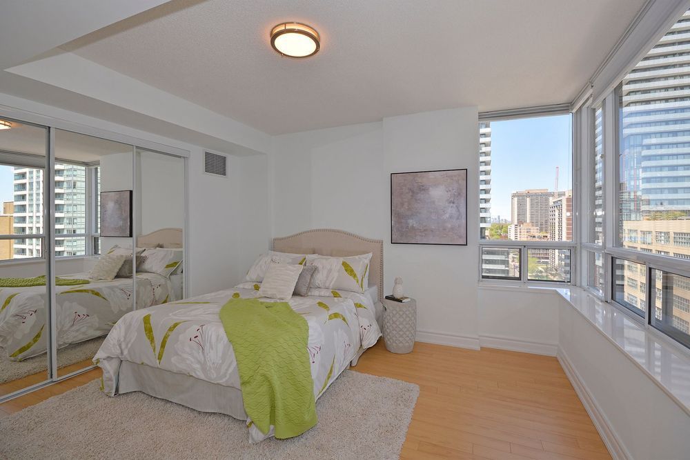Bedroom with bed, mirrored closet, large windows, and area rug.