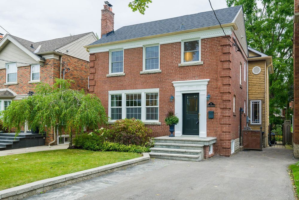 Red brick two-story house with a black front door, steps, and a driveway.