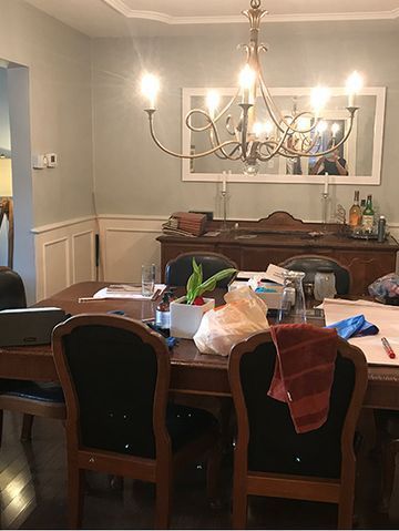 Dining room with table set for a meal. Buffet and mirror on the wall. Chandelier hanging above.