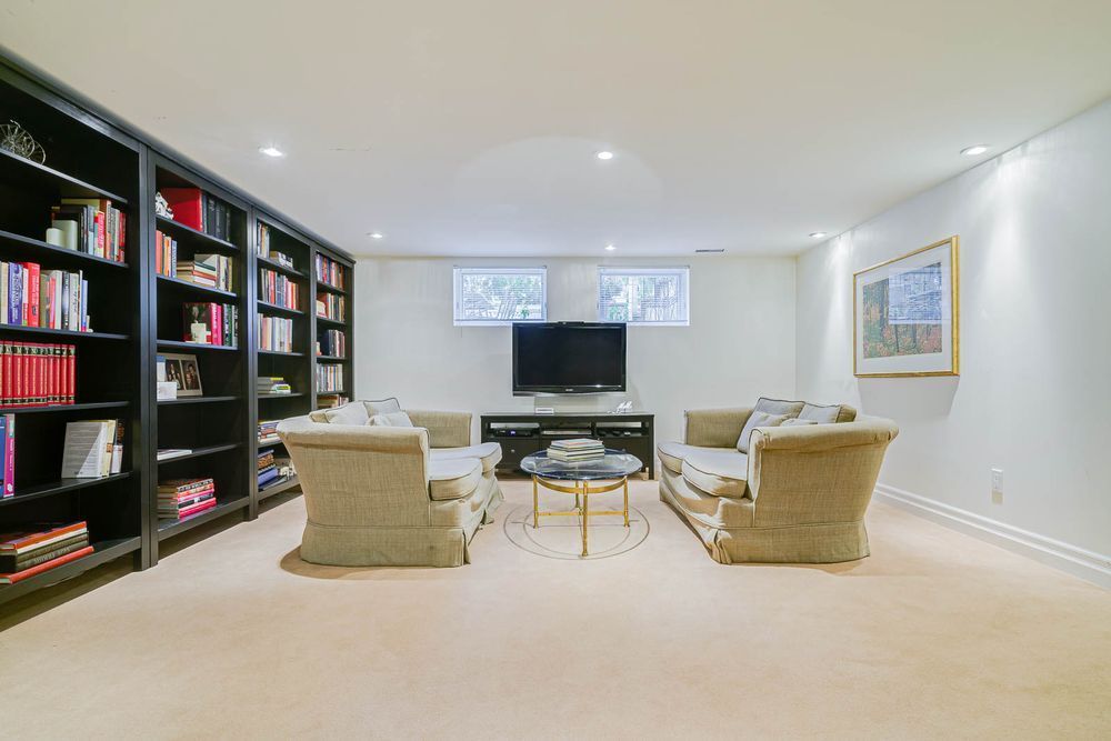 Cozy living room with bookshelves, two sofas facing a TV, and a small table on a light carpet.