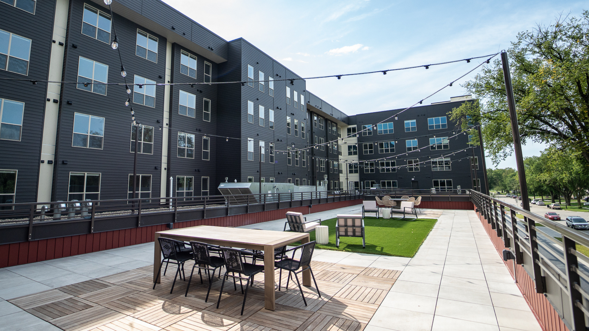 Rooftop patio with outdoor dining set, lounge area, and string lights.