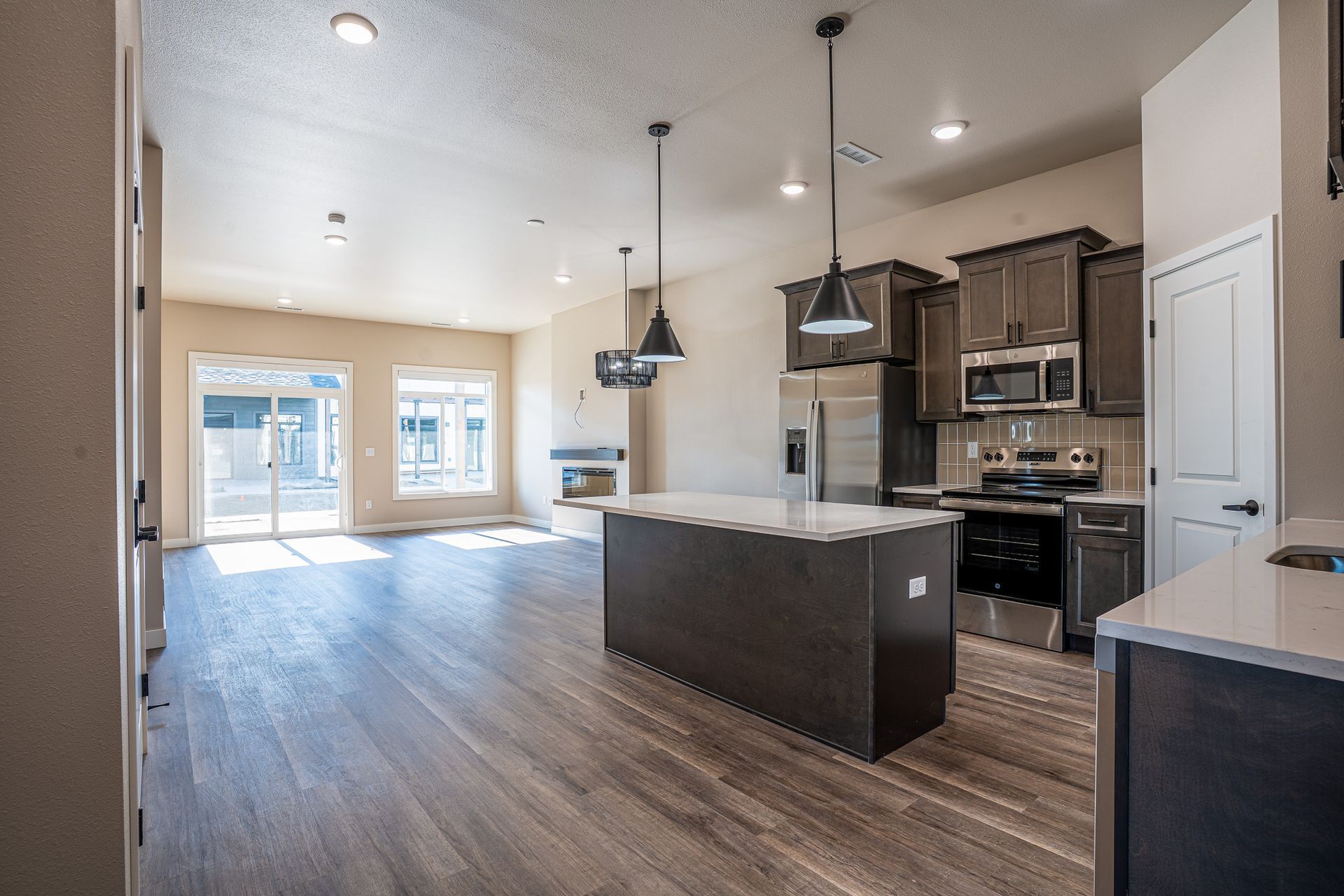 Large kitchen and living room in a townhome with dark wood cabinets and light countertops. 
