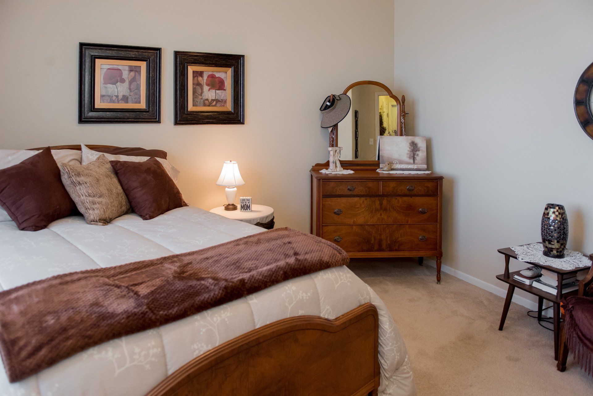 Carpeted bedroom with dresser, bed, and pictures on wall