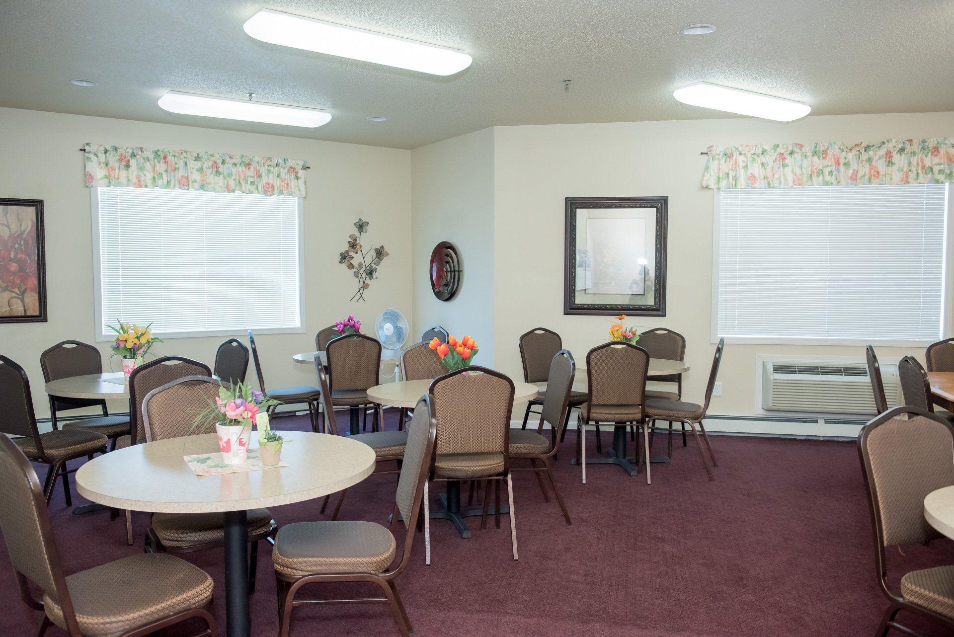 Community room with large windows, air conditioning, and tables.