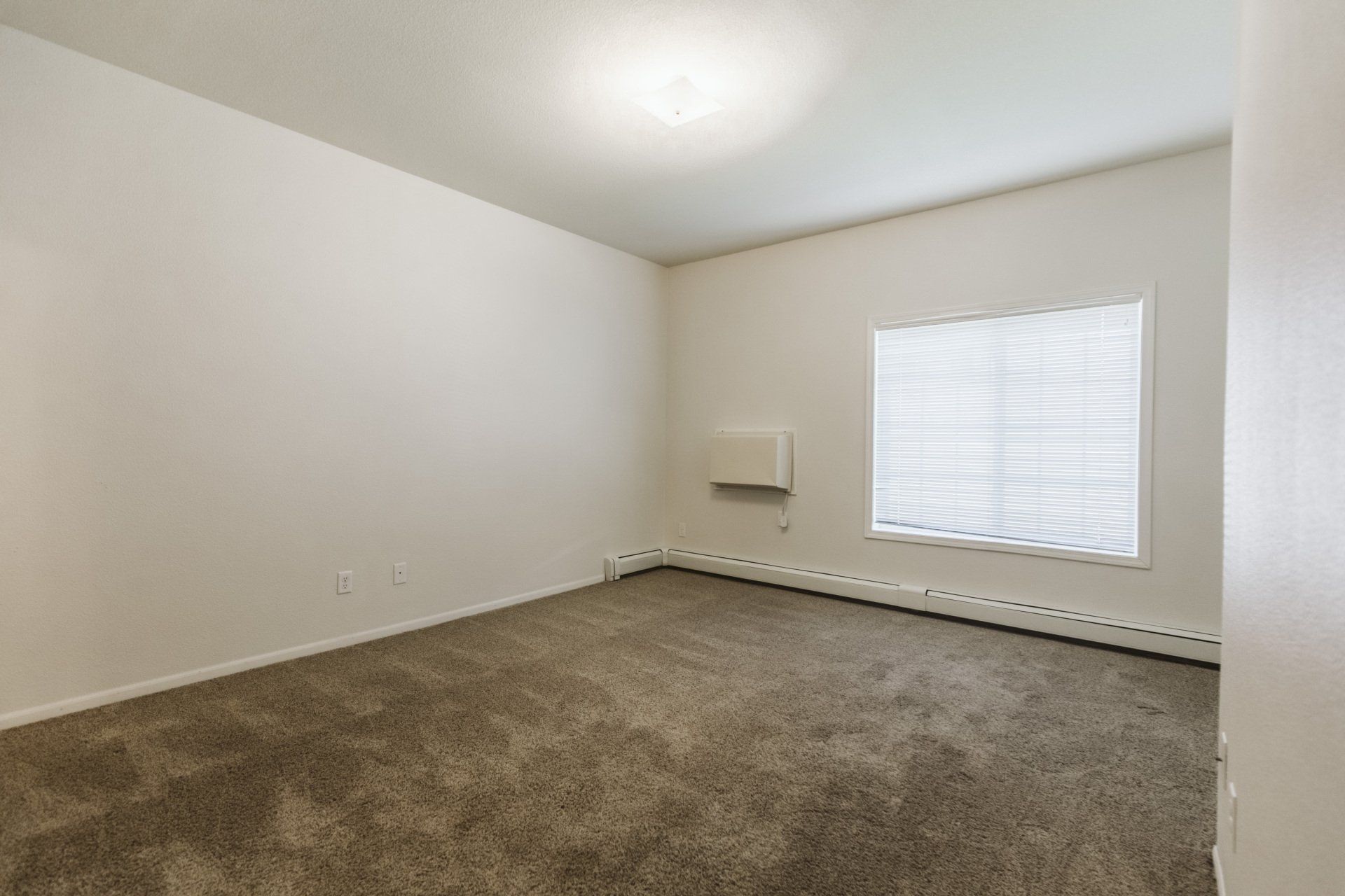 Carpeted bedroom with large window and wall A.C. unit