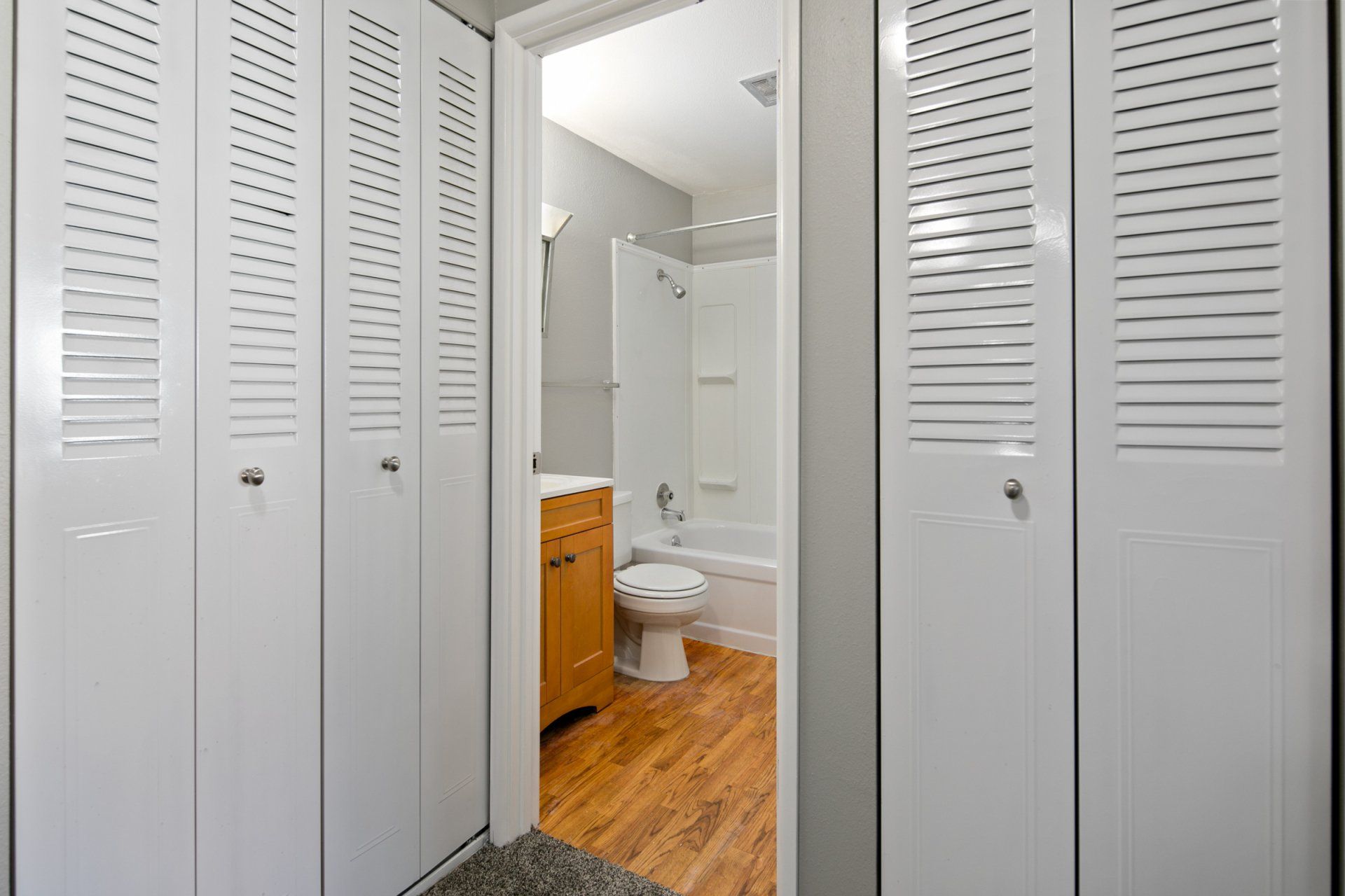 View into bathroom from hallway, with closets on each side of doorway