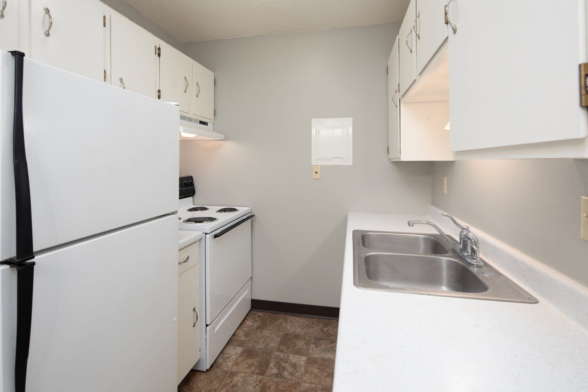 Kitchen with white appliances and long, narrow layout