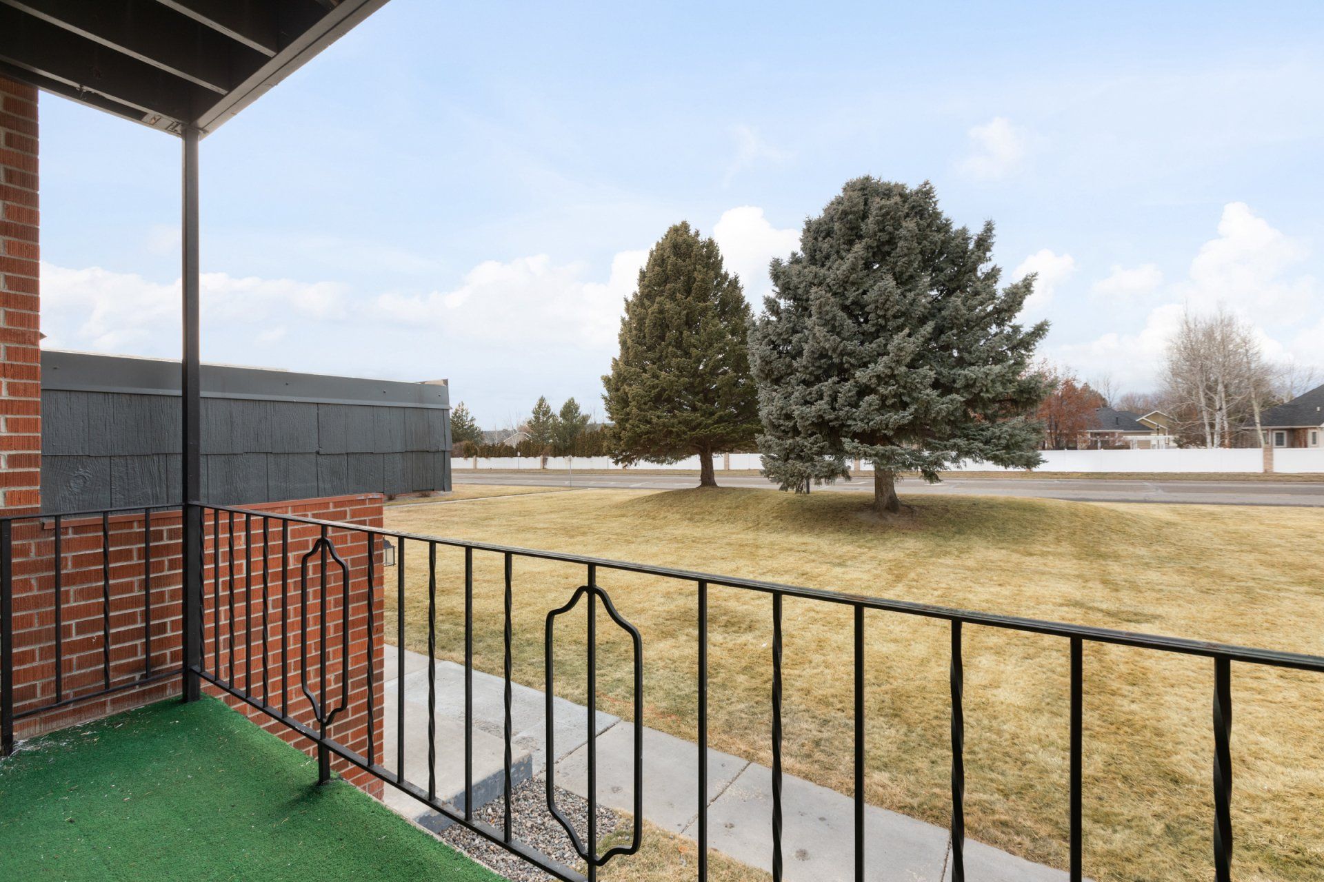Balcony view looking onto grass field with two large trees