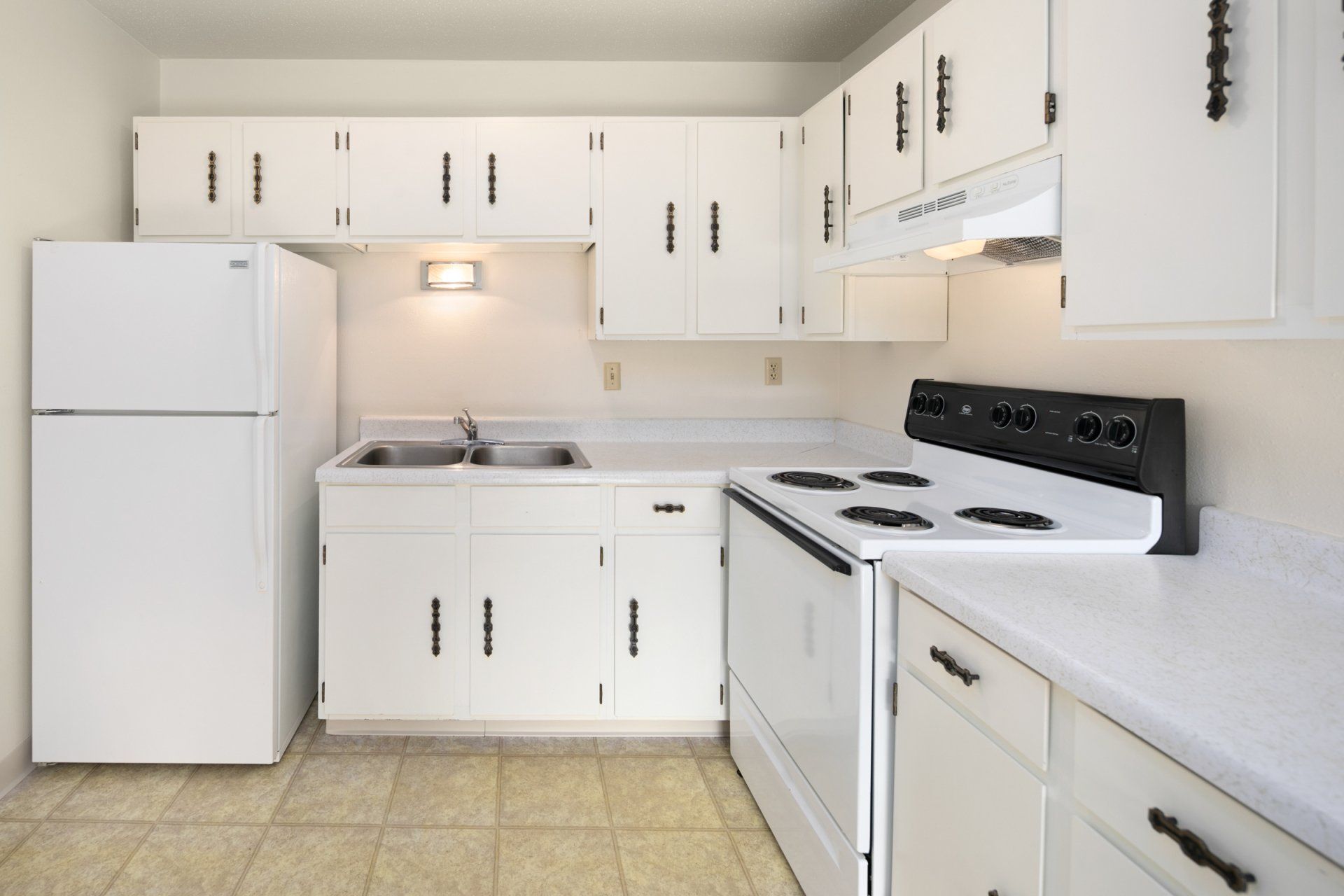 Kitchen with all white cabinetry and appliances, faux-tile floor