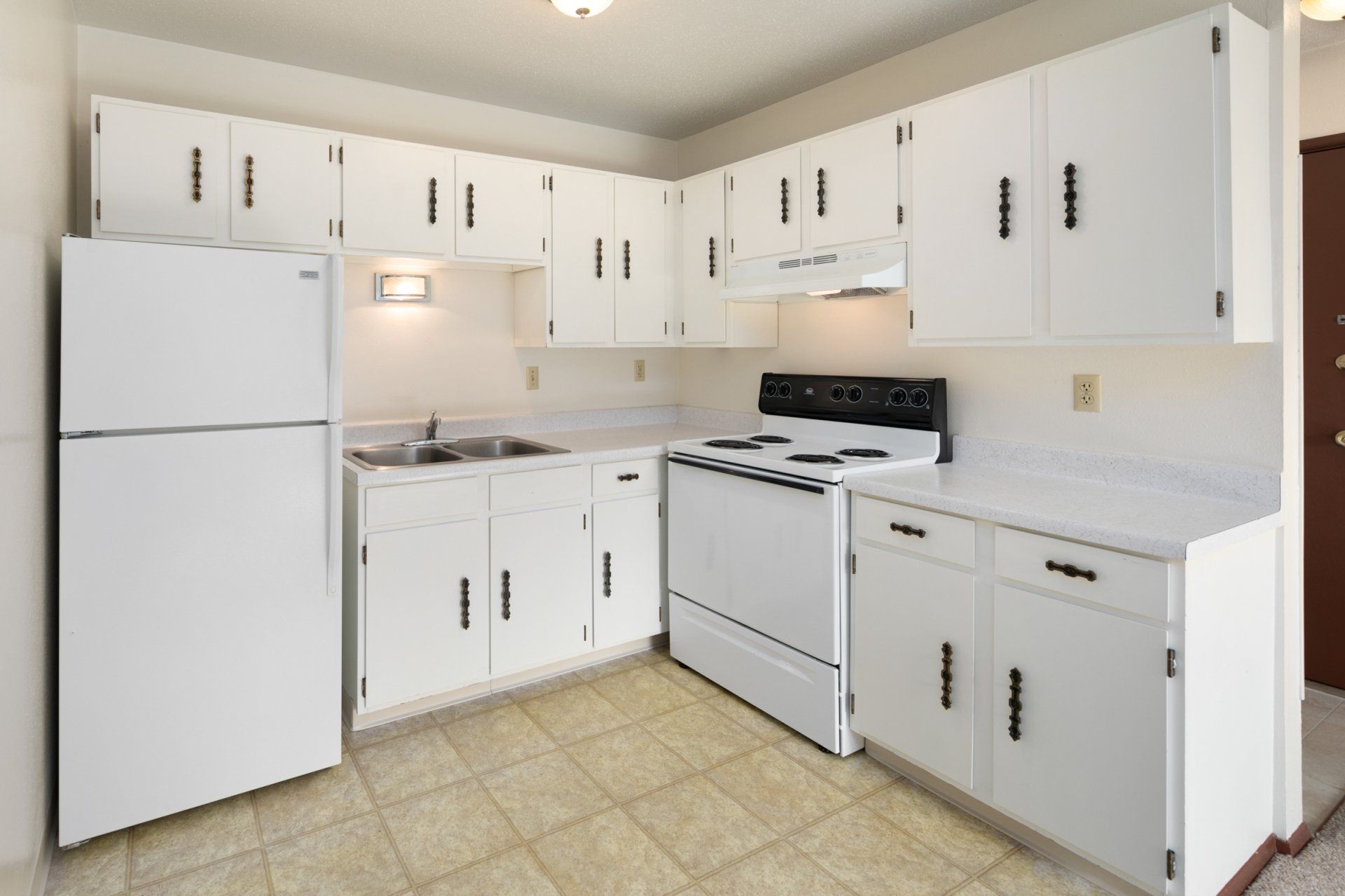 Alternate kitchen with all white cabinetry and appliances, faux-tile floor