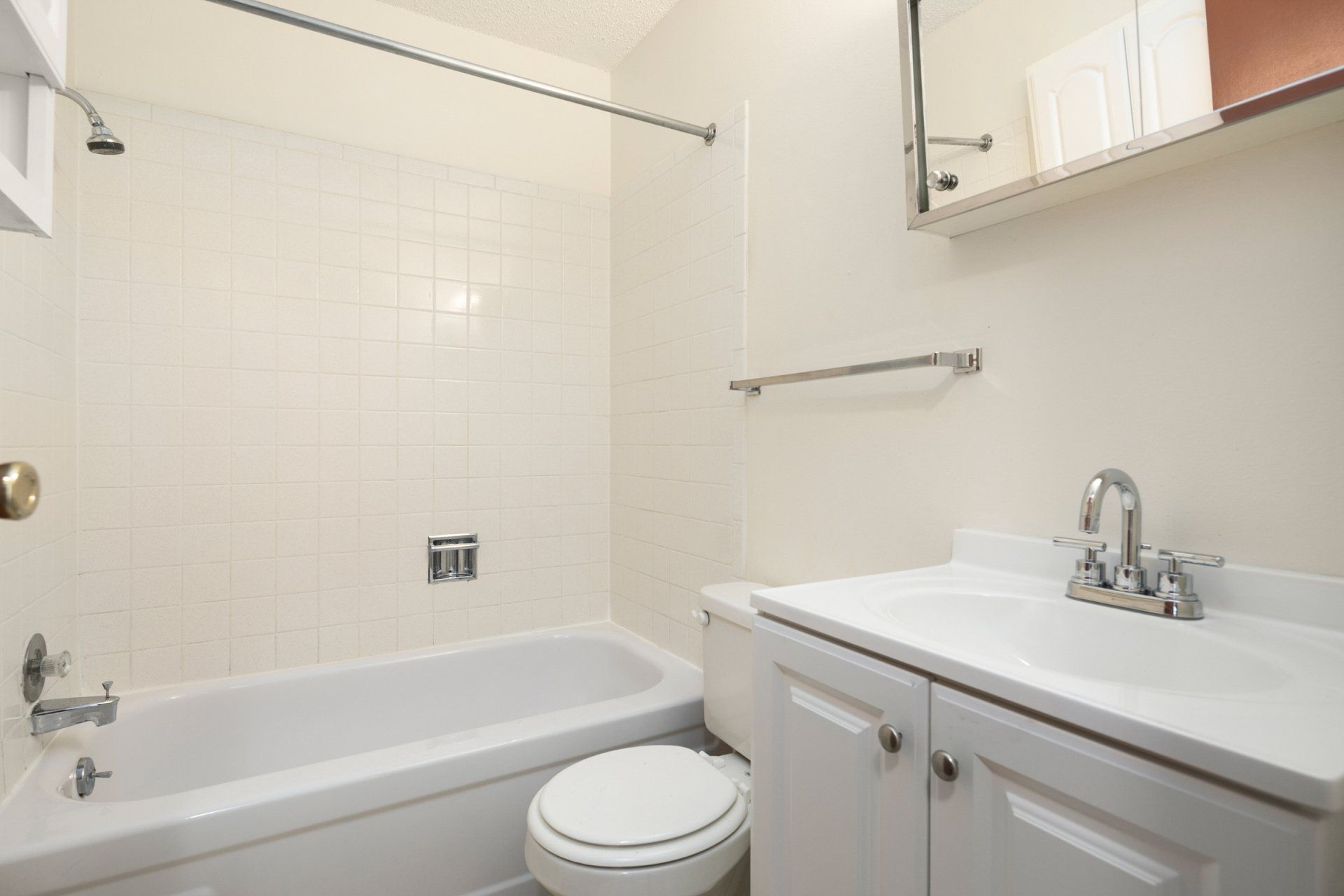 Alternate view of bathroom with shower tub combo, toilet, and white sink with white cabinetry