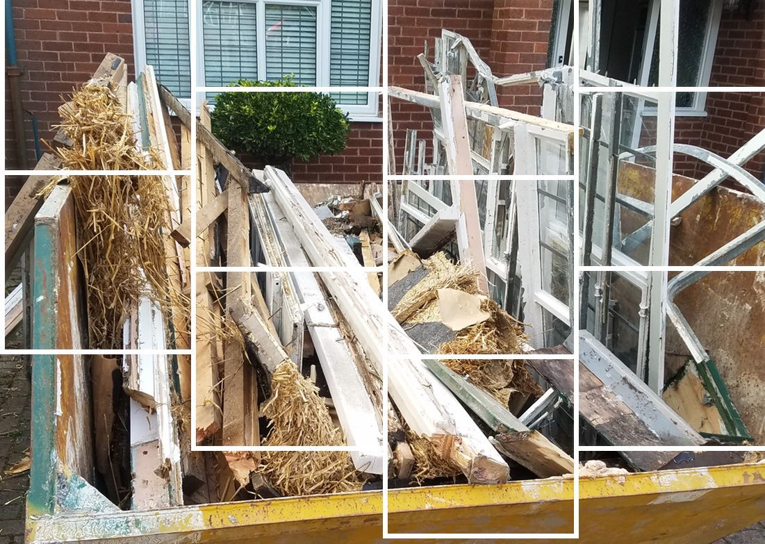 A pile of wood is sitting in front of a brick building.