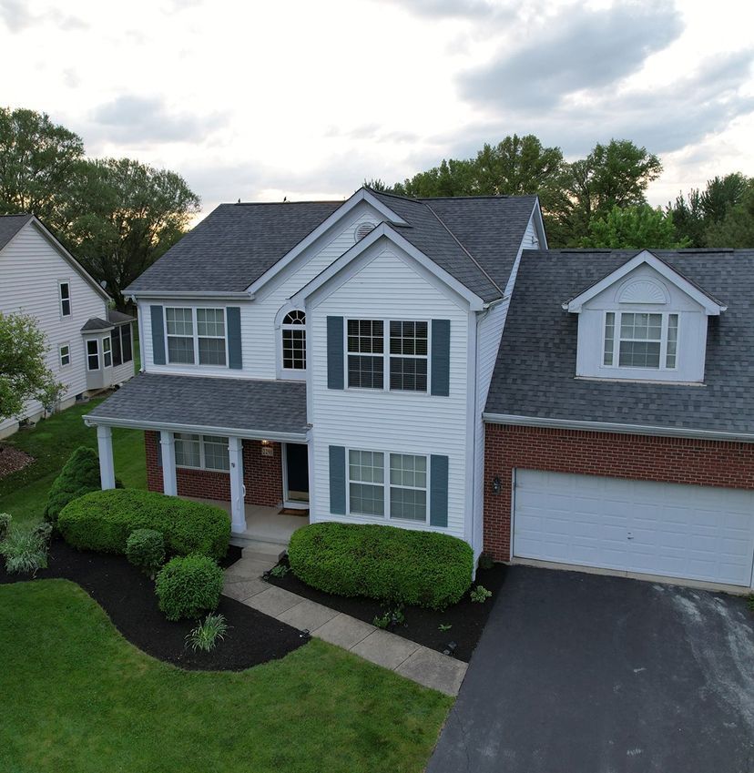An aerial view of a white house with a gray roof
