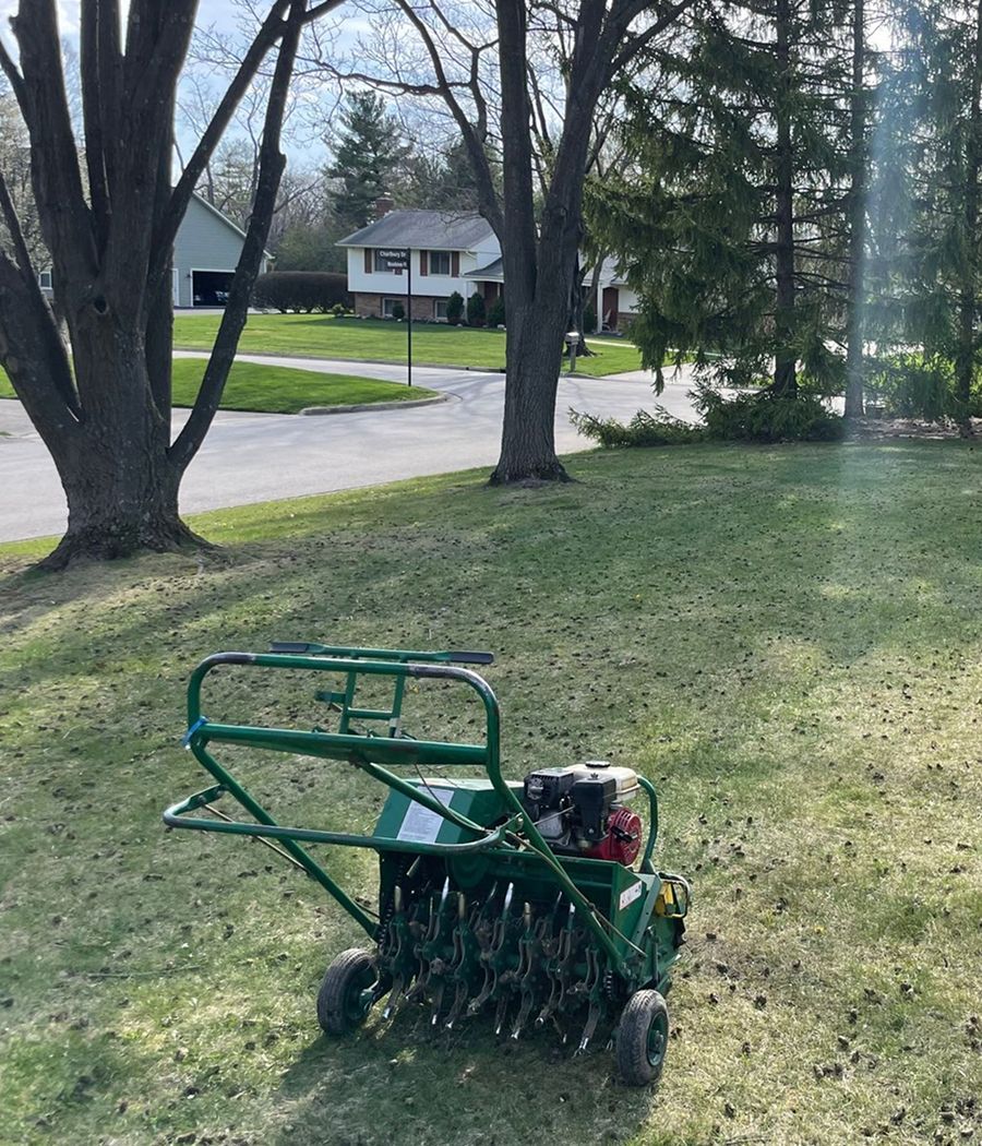 A green lawn aerator is sitting on top of a lush green lawn.