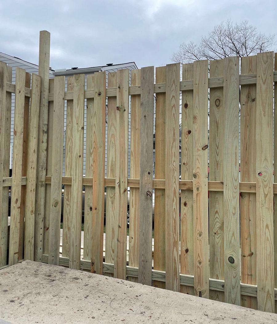 A wooden fence is sitting on top of a dirt field.