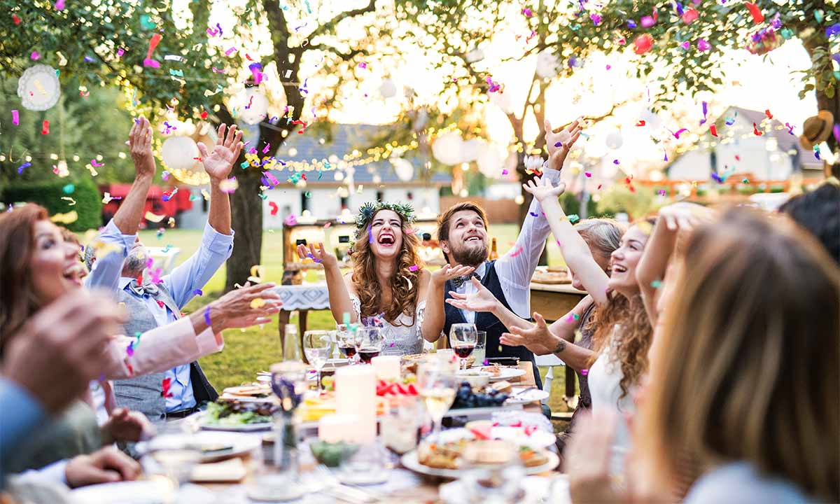 A group of people are sitting at a table throwing confetti in the air.