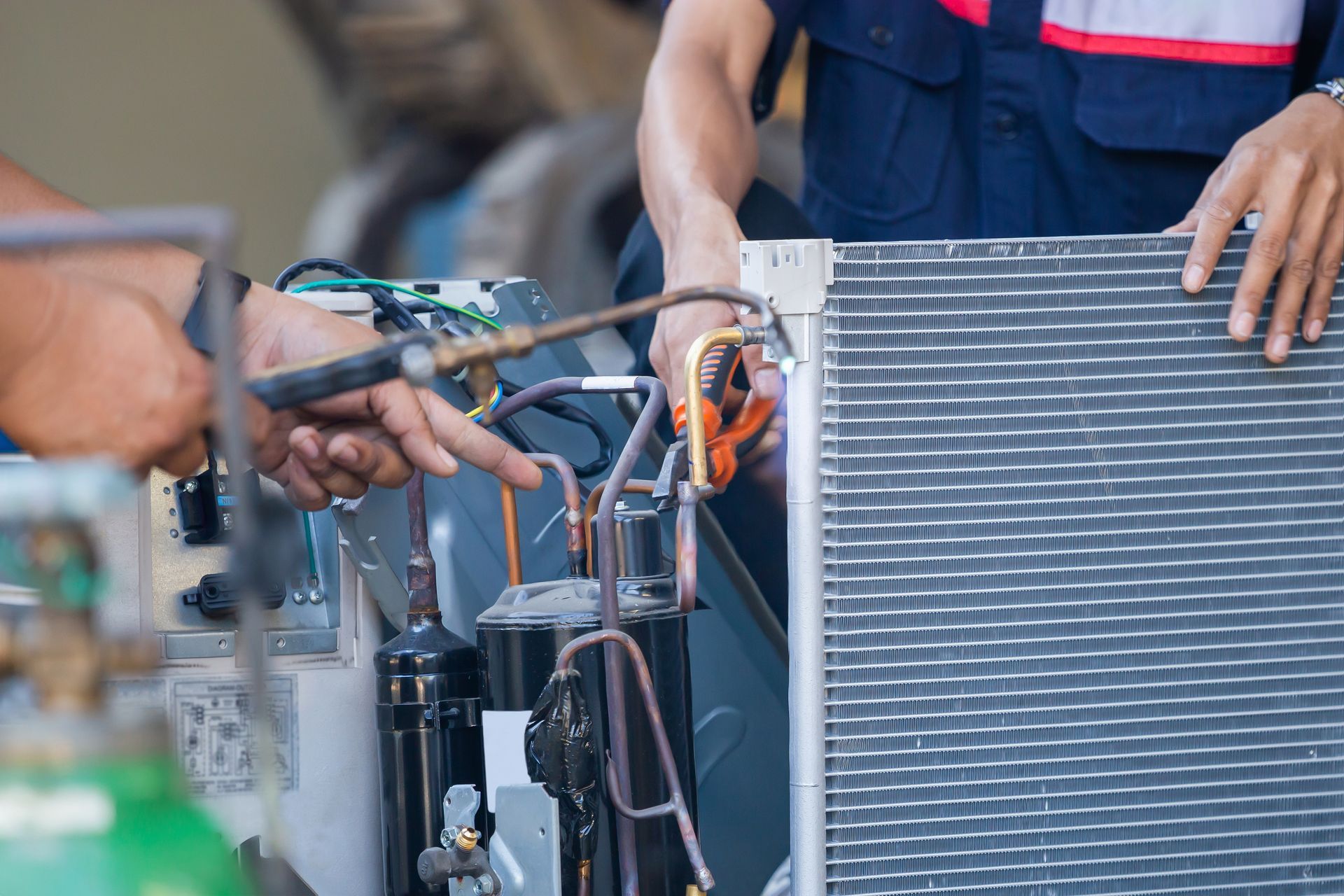 Two men are working on an air conditioner in a garage.