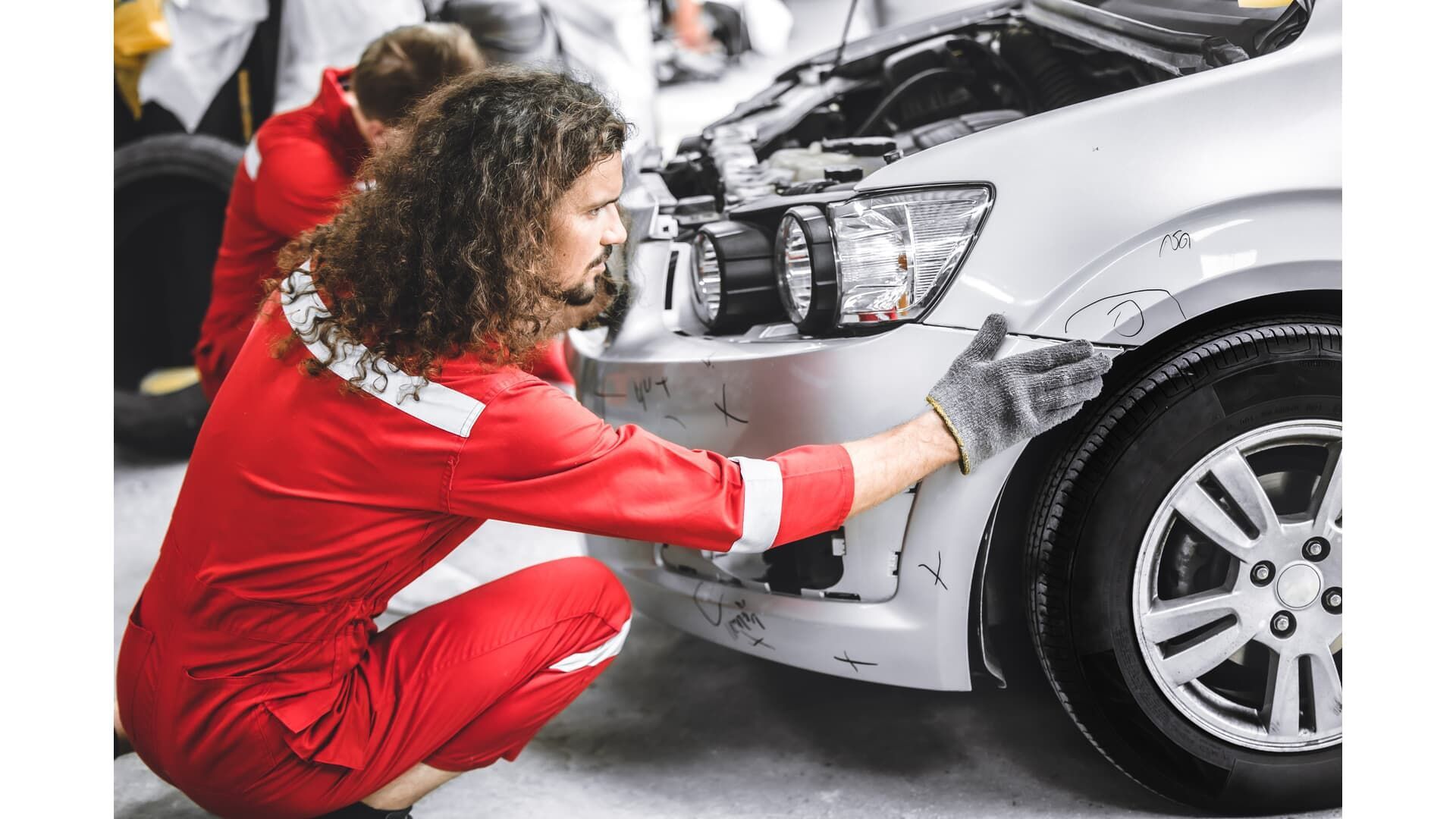 A man and a woman are working on a car in a garage.