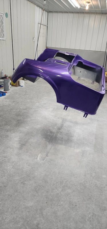 A purple car is floating in the air in a garage.