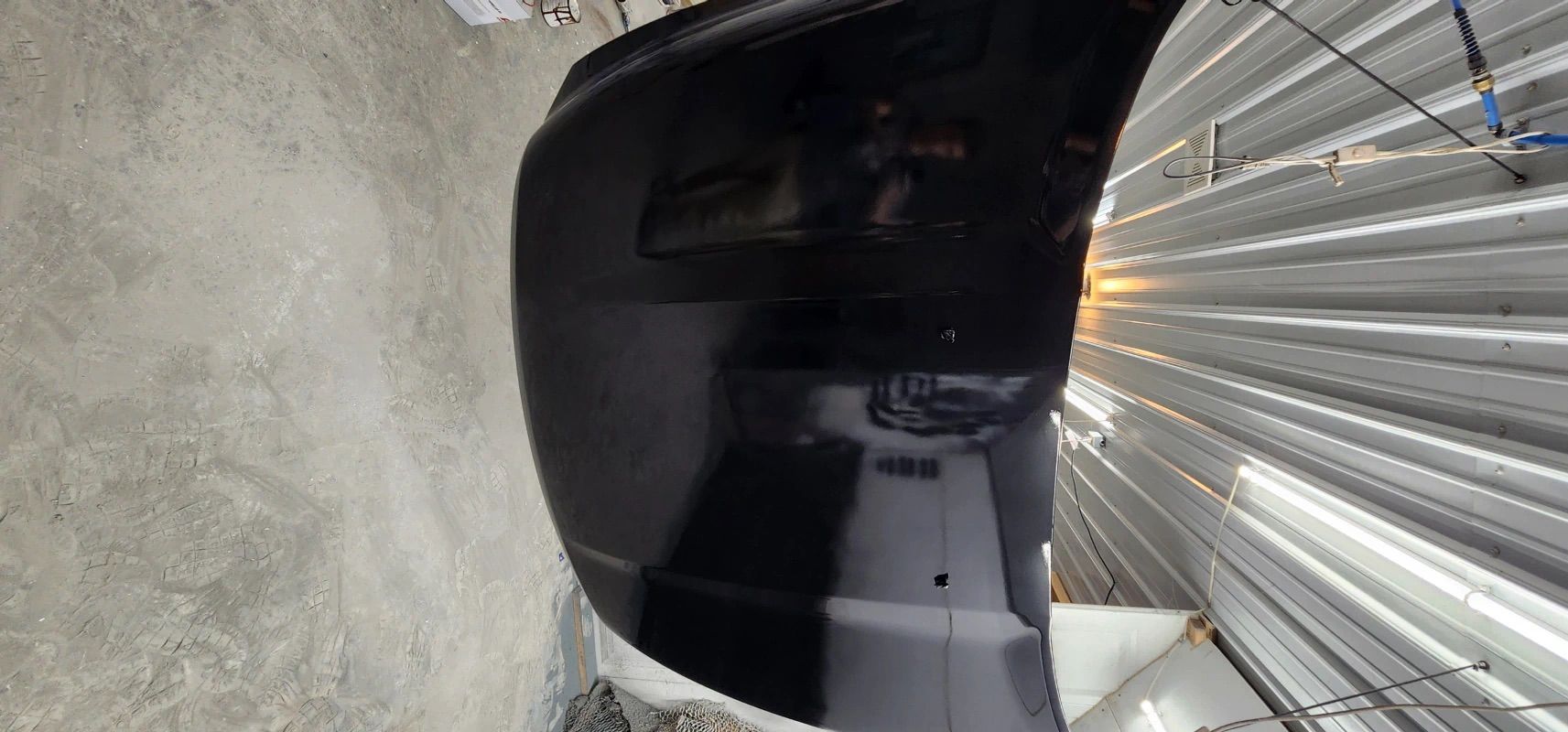 A black car is parked in front of a metal wall.