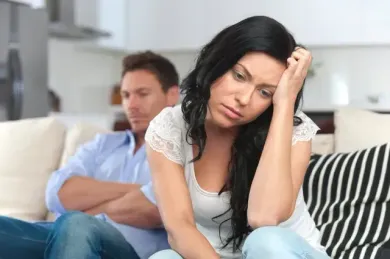 A man and a woman are sitting on a couch with their arms crossed.