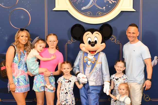 Family poses with Mickey Mouse at Disney World.