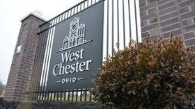 Sign for West Chester, Ohio, with town's building silhouette, on a black backdrop with a brick pillar.