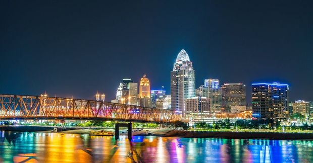 Cincinnati skyline at night with a bridge over a body of water.