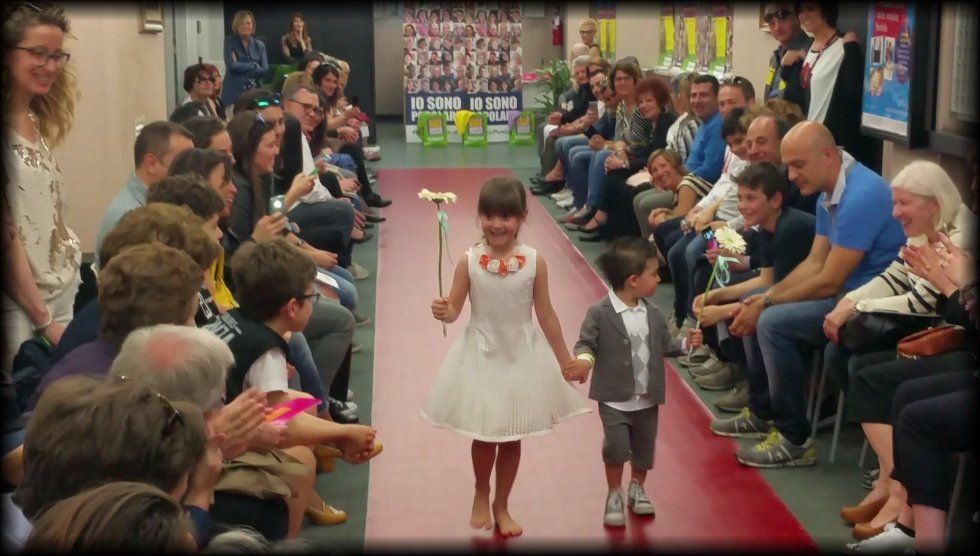 bambina con abito per cerimonie durante una sfilata di moda