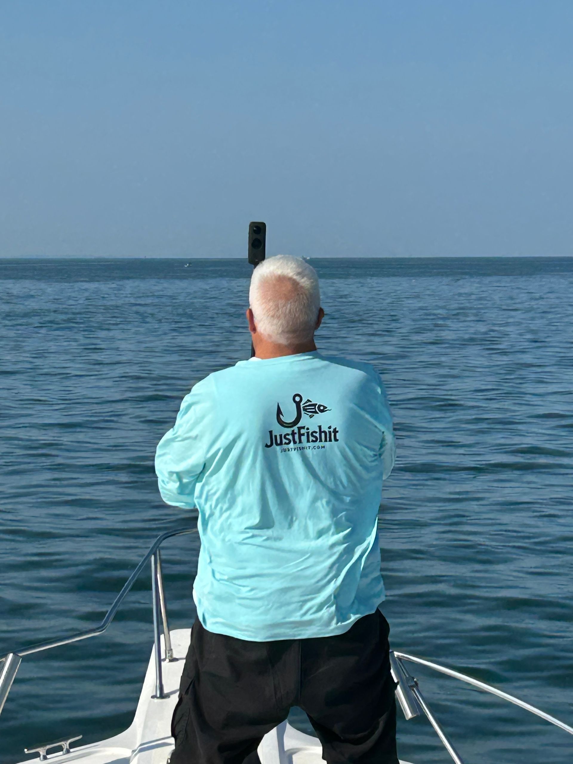 Man on boat facing the ocean, wearing a light blue 