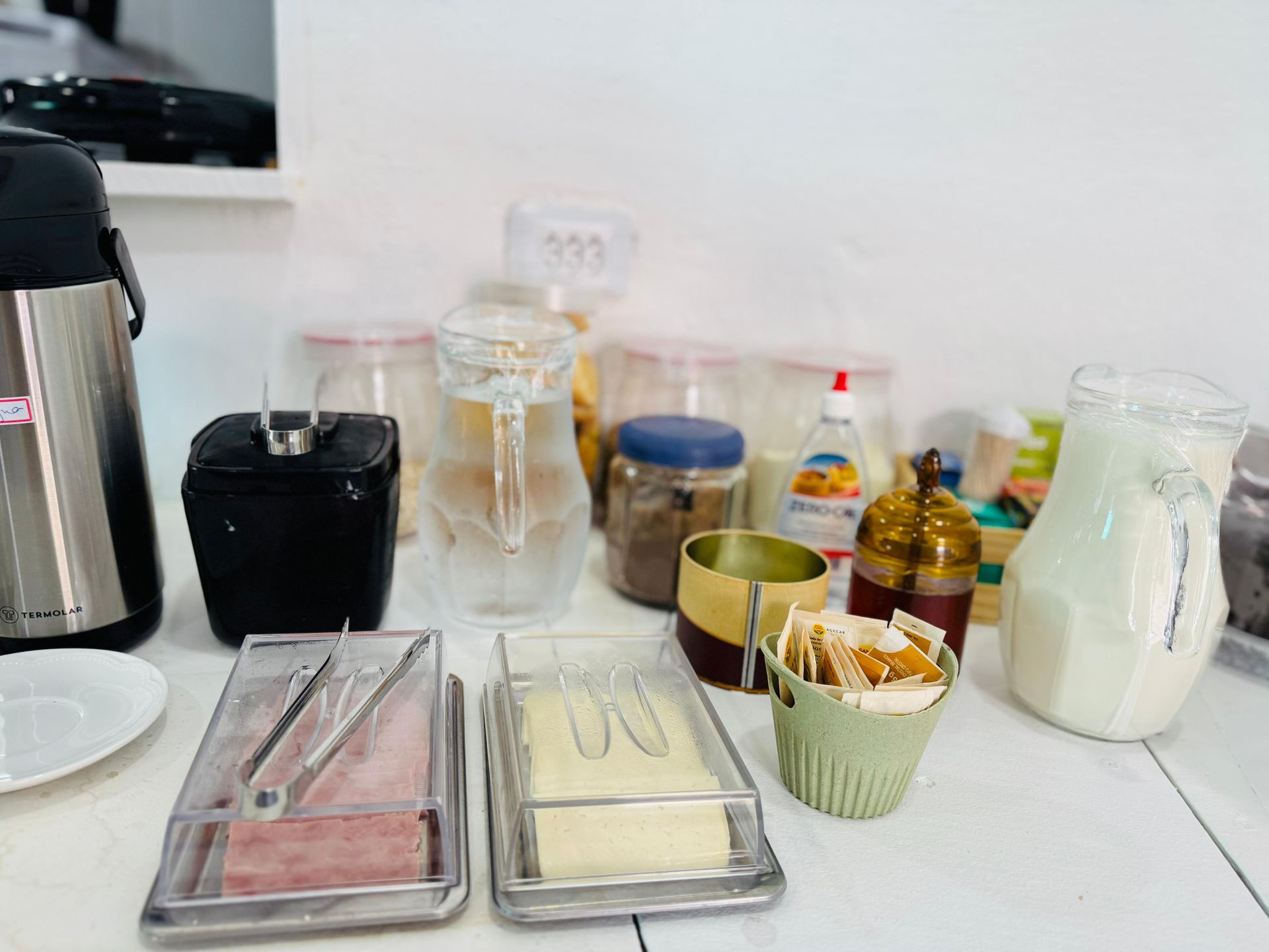 Uma mesa de bufê com diversos itens: bebidas, condimentos e pão.