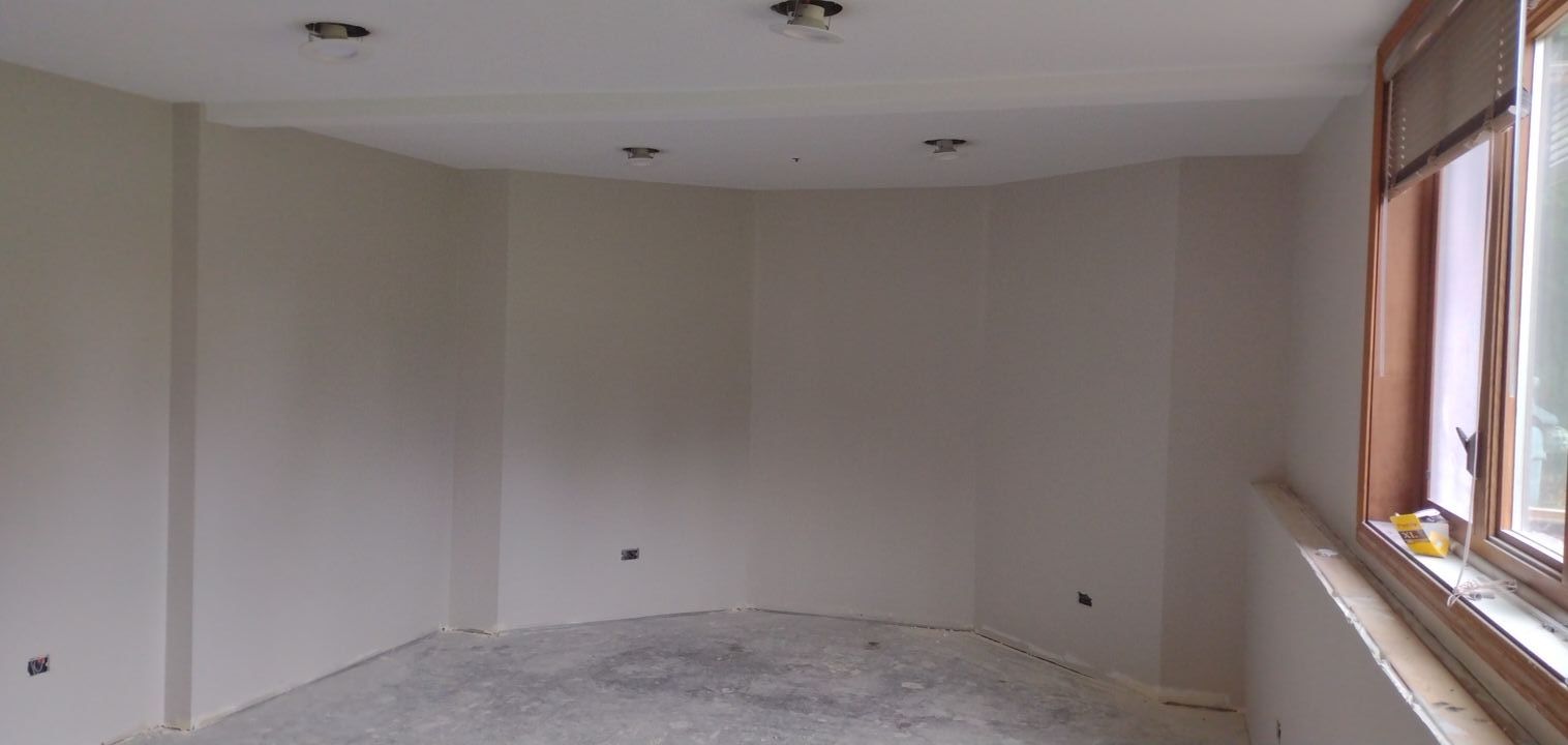 An empty hallway with white walls and concrete floors in a house under construction.