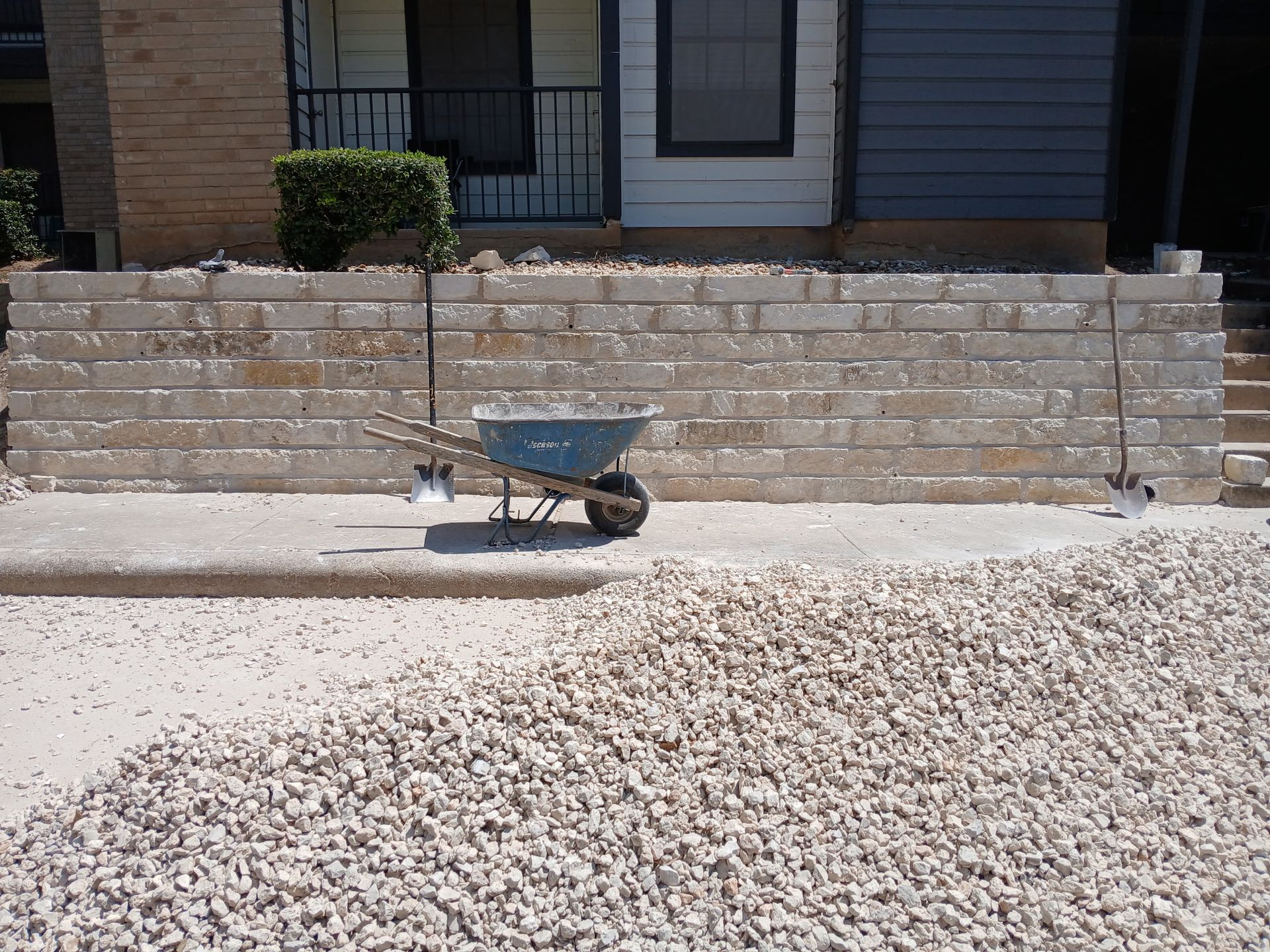 A wheelbarrow is parked in front of a brick wall