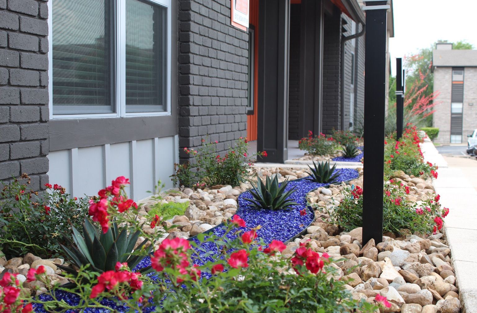 A brick house with a garden in front of it filled with flowers and rocks.