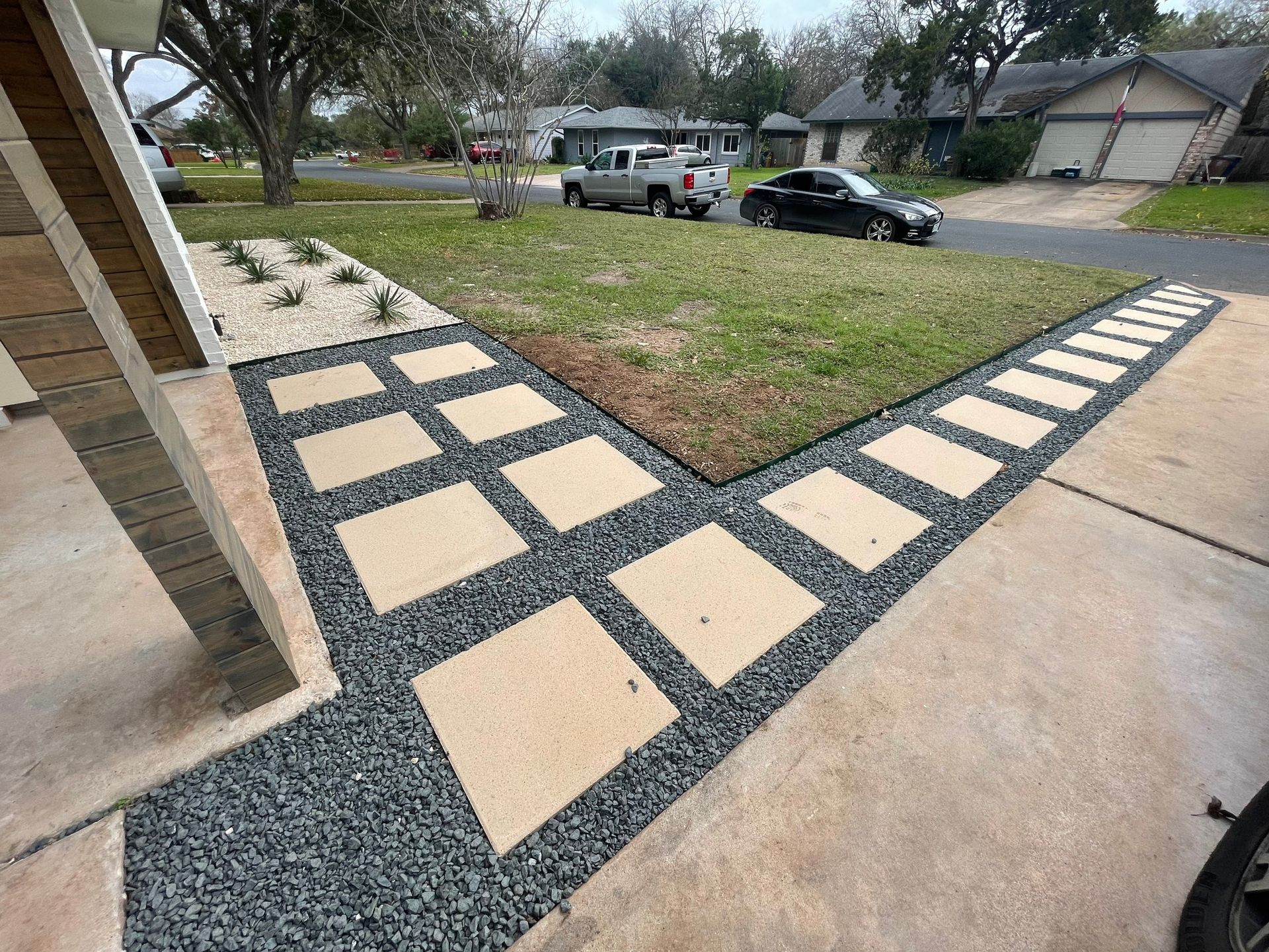 A driveway with a concrete walkway and gravel in front of a house.
