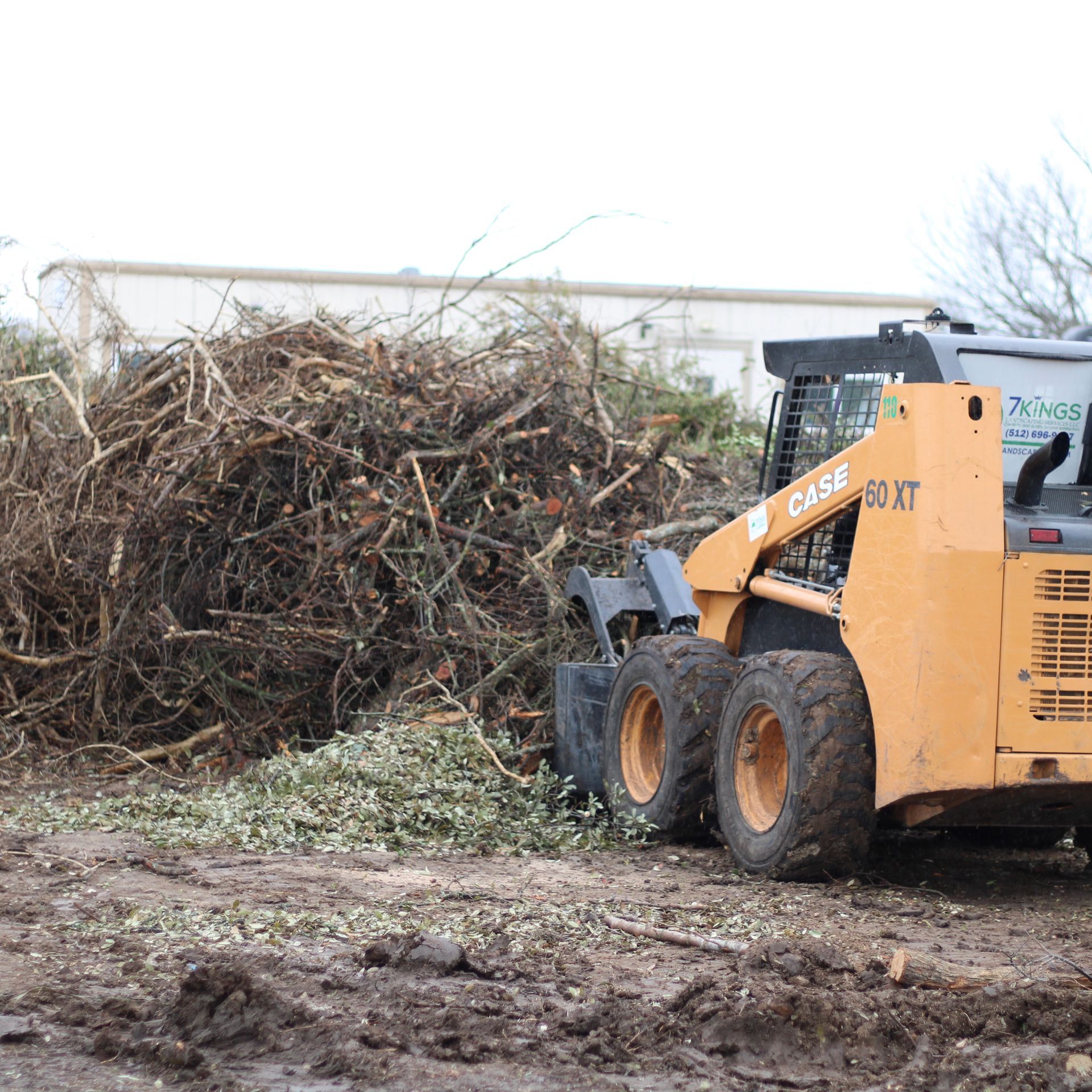 A case skid steer is parked in front of a pile of branches