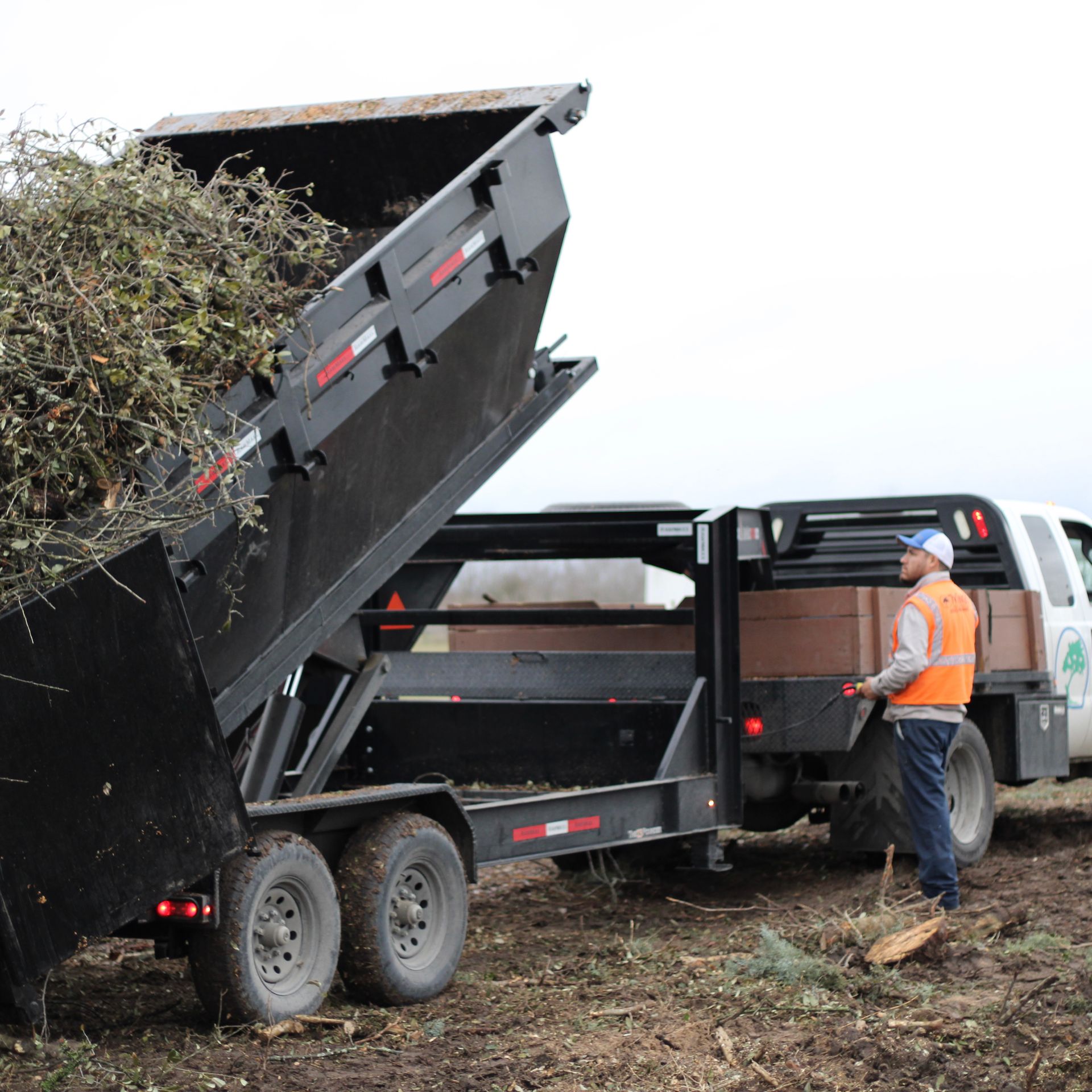 A man in an orange vest is standing next to a dump truck